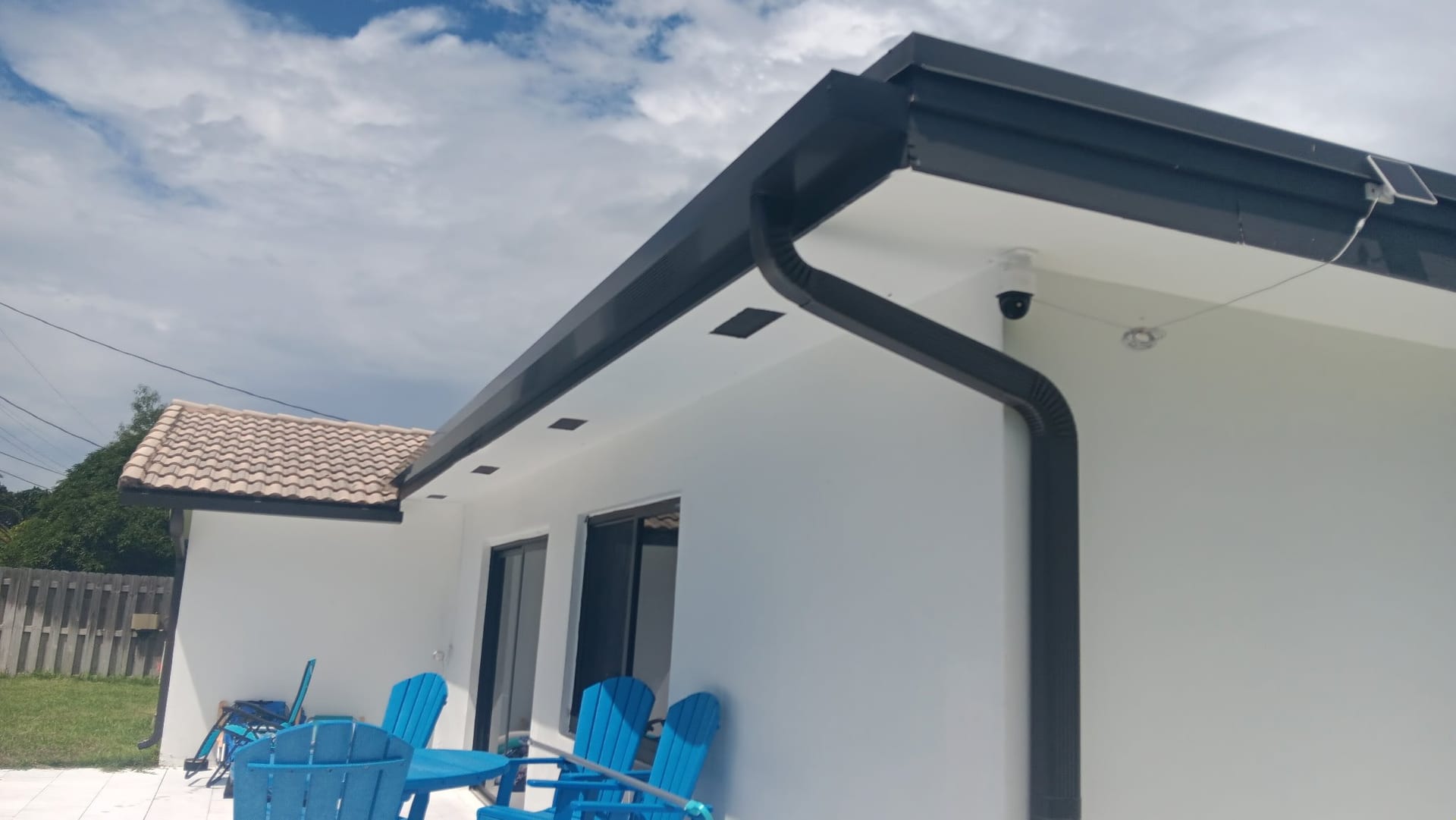 Dark bronze seamless gutter and downspout on a white stucco house, installed by DL Rescreening and Gutters
